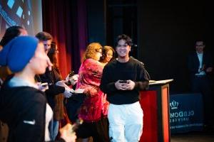 A student walks across a stage holding an award.